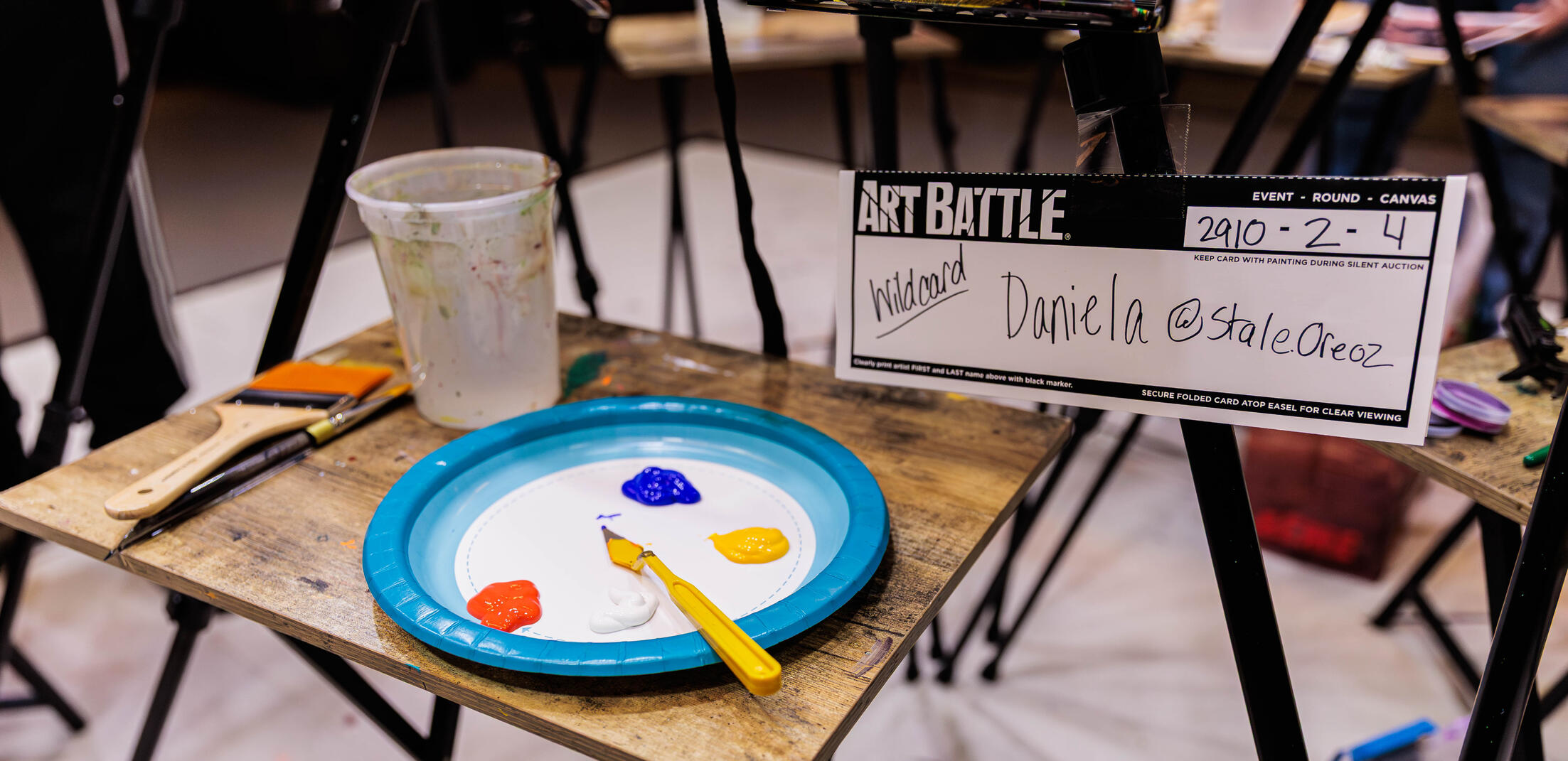 Art Battle Label Daniela's nametag for the event Art Battle taken by @black_fyre_photos on instagram. Also a directory to the About Me tab.